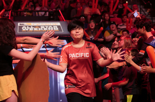 Geguri, wearing a red Shangai Dragons jersey, exits into a crowded stadium and gives high fives to fans